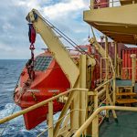 Davits_holding_red_lifeboat_on_board_of_the_container_vessel.