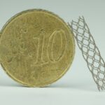 3D-gedruckter_Stent_(Nickel-Titan-Legierung)_im_Größenvergleich_mit_einer_10-Euro-Cent-Münze