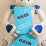 Humanoider Roboter Nao mit Buch über 33 Fragen und Antworten zur KI